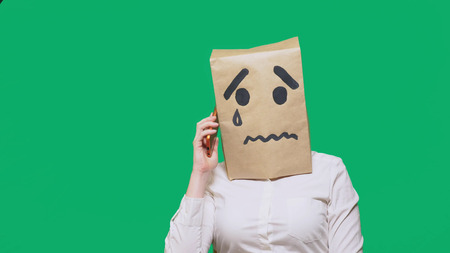 concept of emotion, gestures. a man with a package on his head, with a painted smiley crying, sad, talking on the phone.の写真素材