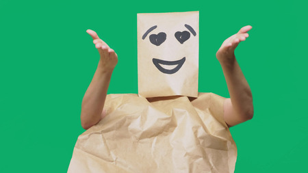 concept of emotions, gestures. a man with paper bags on his head, with a painted emoticon, smile, joy, love eyesの写真素材