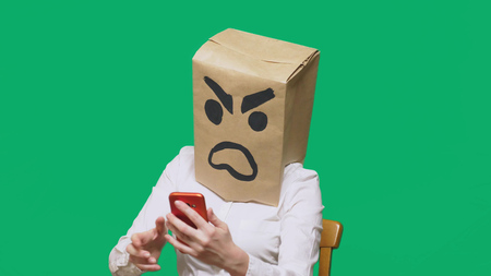 concept of emotion, gestures. a man with a package on his head, with a painted smiley aggressive, angryの写真素材