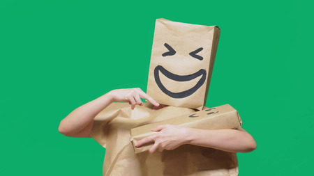 concept of emotions, gestures. man with a package on his head, with a painted emoticon, smile, joy, laughter. plays with the child painted on the boxの写真素材