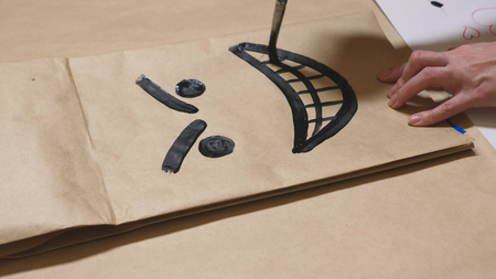 The girl draws with a brush on paper bags various emotions. The concept of emotions in smileys.の写真素材