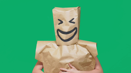 concept of emotions, gestures. a man with paper bags on his head, with a painted emoticon, smile, joy.の写真素材