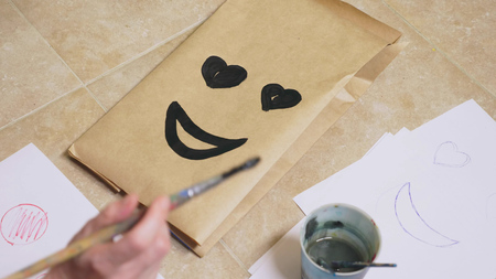 The girl draws with a brush on paper bags various emotions. The concept of emotions in smileys.の写真素材