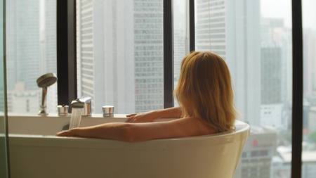 Beautiful Woman enjoying relaxing bath in luxury bathroom with a window. Lifestyle and beauty care...