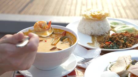 prawn spicy soup is a Thai dish with sour and spicy taste. some are scooping prawn spicy soup....