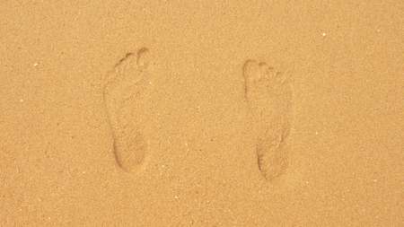 traces on the sand disappearing under the sea wavesの写真素材