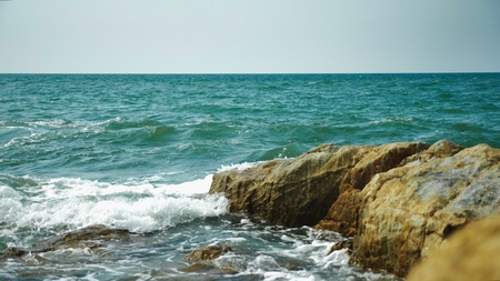 Wet sea stones in the sand at low tide. Waves and sea foam.の写真素材