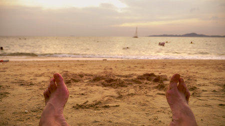 Men's Legs on the sea sand and wave, Relaxation on the ocean beach, Summer holidaysの写真素材