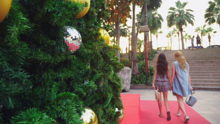 happy mom and daughter on the background of the Christmas tree in a tropical city. The concept of...