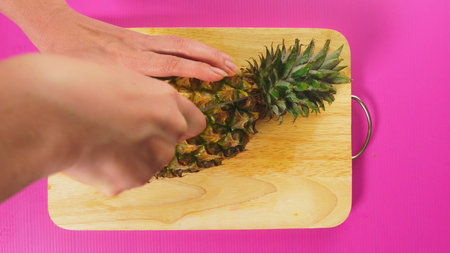 top view, female hand cuts the fruit with a knife on a wooden board, pineapple. The concept of natural healthy foodの写真素材
