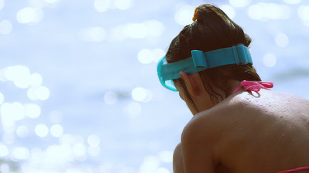 girl in an underwater mask sits on the shore.の写真素材