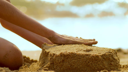 girl builds a sand castle on a tropical beach. close-up.