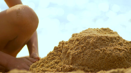 girl builds a sand castle on a tropical beach. close-up.の写真素材