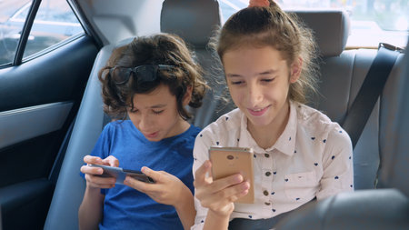 twins brother and sister use the phone while traveling in the car