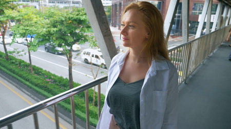 charming young woman with golden hair, walking in the center of the city, she walks across the bridgeの写真素材