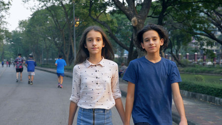 Portrait of teenagers, boy and girl walking in nature in a big park with pleasure, brother and sister twins are walking together in a city parkの写真素材