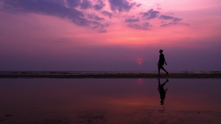 silhouette. lonely asian young man walking peacefully along a deserted beach at sunset. seascapeの写真素材