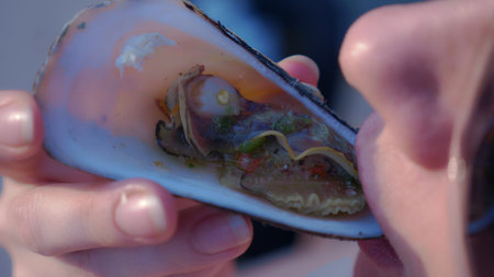 close-up lips. Woman eating shellfish. Seafood and Mediterranean cuisine with mussels in the shell. Diet and health concept.の写真素材