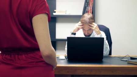 Office flirt. Attractive woman in red overalls with a deep neckline flirting at the table with her...