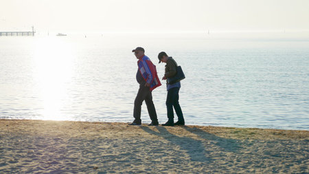 Senior couple walking at the beach on the northern sea. Spending time together.