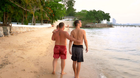 LGBT concept. Happy gay couple with little child are resting on the beautiful tropical beach.の写真素材