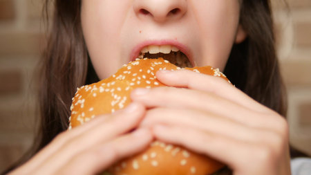 close. childs mouth. girl eating a hamburgerの写真素材