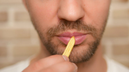 close-up. male mouth. man eating french fries.の写真素材