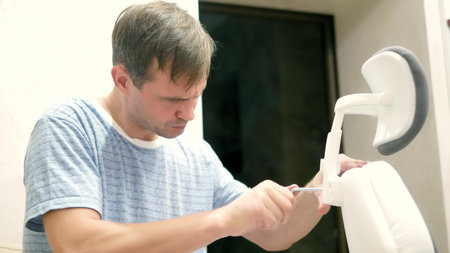 a young man is assembling an office chair. The concept of repair and assembly of furniture