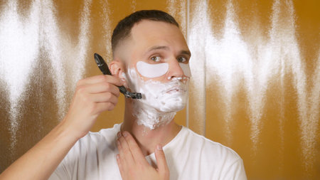 Portrait of a handsome man with eye mask, who shaves with a shaving razor in the bathroom. Metrosexual conceptの写真素材