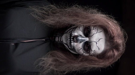 concept, beautiful makeup for halloween. Portrait of a young sexy girl with skull makeup. on a black...