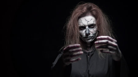 concept, beautiful makeup for halloween. Portrait of a young sexy girl with skull makeup. on a black background, face in the dark. close-upの写真素材