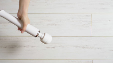 White female vibrator on a white wooden floor, turns on and moves on the floorの写真素材