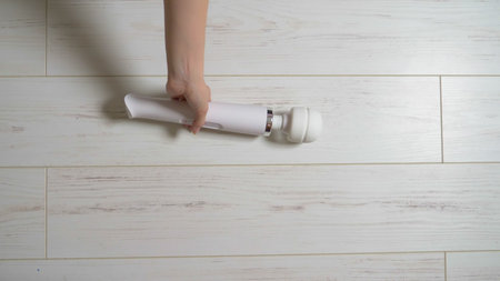 White female vibrator on a white wooden floor, turns on and moves on the floor.の写真素材