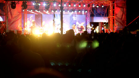 rock concert in the evening. people in the crowd raise their hands and applaudの写真素材