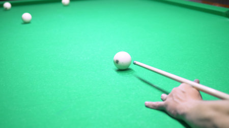billiards. Close-up. man hand with cue and white ball on a green pool table. copy space.