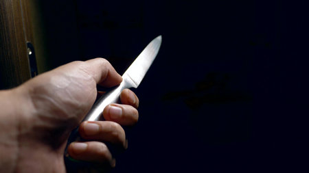 concept of halloween, violence. first-person view. male hand with a knife moves along a dark corridor.の写真素材