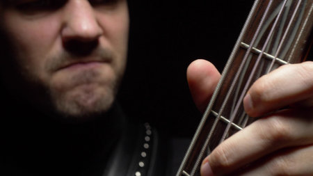 male face and fretboard of electric guitar on black background.