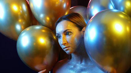 closeup girl face with Golden sequins among the Golden balloonsの写真素材