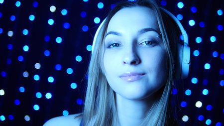 portrait of a girl in headphones in neon light on a background garlands