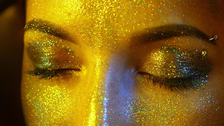 closeup girl face with closed eyes with gold sequins on the skinの写真素材