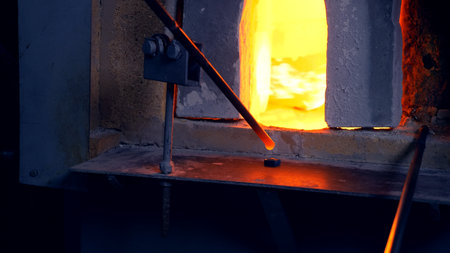 glassblower. manufacturer of glass products. man heats glass in a furnace