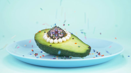 fashion design food. half an avocado with a pearls, glass ball, confettiの写真素材
