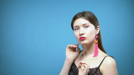 portrait of a beautiful girl. blue background. the girl wears earringsの写真素材
