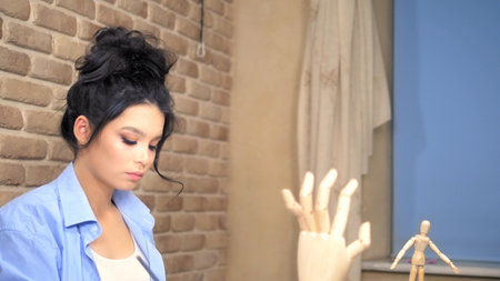 beautiful brunette girl draws a sketch with a wooden mannequin
