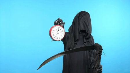 A man in a death suit with a scythe, shows a clock. blue backgroundの写真素材
