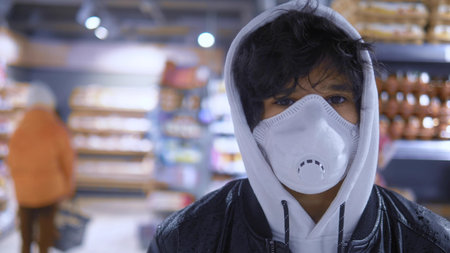 Portrait. brunette guy in a medical mask in a store. pandemicの写真素材