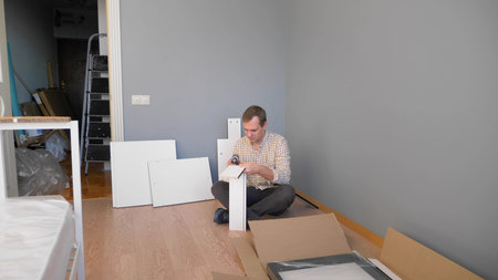 handsome man collects furniture at home in the room. copy space