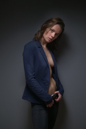 beautiful slender woman in a strict jacket on a naked body. grey backgroundの写真素材