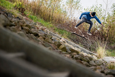 Boy doing skateboard trick on bankの写真素材