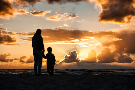 A woman holding a child's hand during sunsetの写真素材